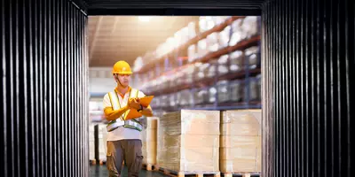 Worker Holds A Clipboard Checking the Loading Cargo Shipment at Distribution Warehouse. 